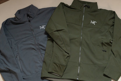 Two jackets, one blue and one green, with a brand logo on a neutral background