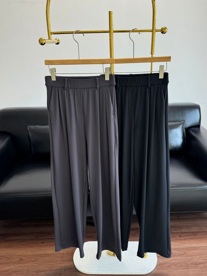 Black pants hanging on a gold rack with a black sofa in the background